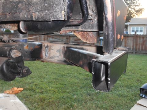 1972 Ford Bronco - Close-up view of the rear frame and a newly welded square tube bumper extension on a vehicle, likely a 1972 Ford Bronco, outdoors on a gras…