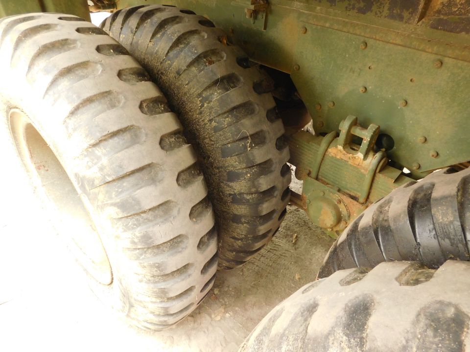 Close-up of large, rugged tires and suspension on an olive-drab vehicle.