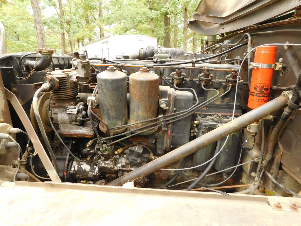 Close-up of a large diesel engine with hoses, filters, and an orange 'QUICK START' canister.