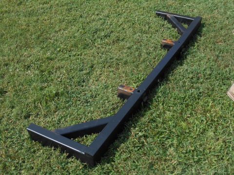 1972 Ford Bronco - A black metal trailer hitch receiver is laid out on a grassy lawn. The hitch has two mounting brackets and a long, rectangular receiver tub…