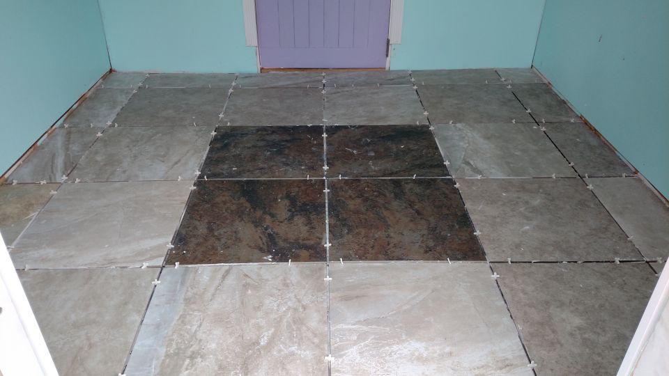 Tiled floor with gray and dark accent tiles by a purple door