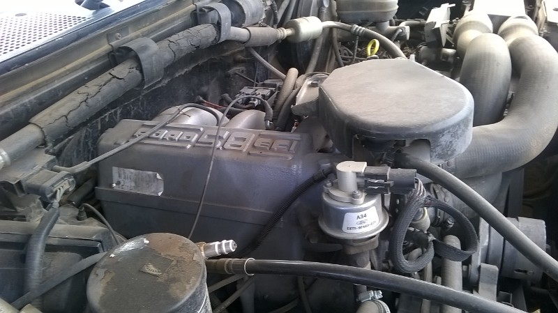 Dusty engine bay of a 1991 Ford Bronco, showing the 4.6L EFI intake manifold and hoses.