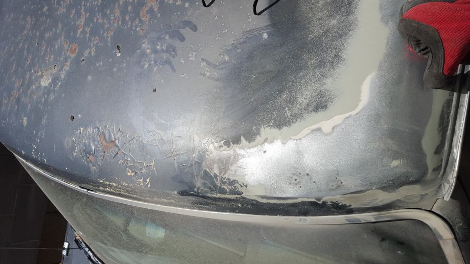 Vehicle body panel with rust and body filler application.