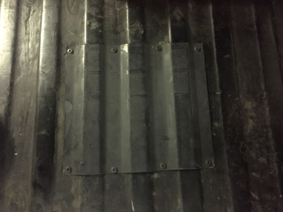 Corrugated plastic patch screwed onto a ribbed dark truck bed.