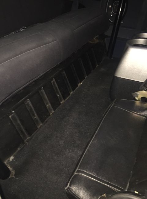 1988 Ford Bronco - The interior of a vehicle shows black carpeting on the floor and black upholstery on the seats. A black ribbed panel runs along the lower p…