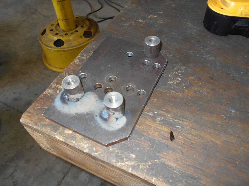 Metal plate with threaded posts welded on a workbench.