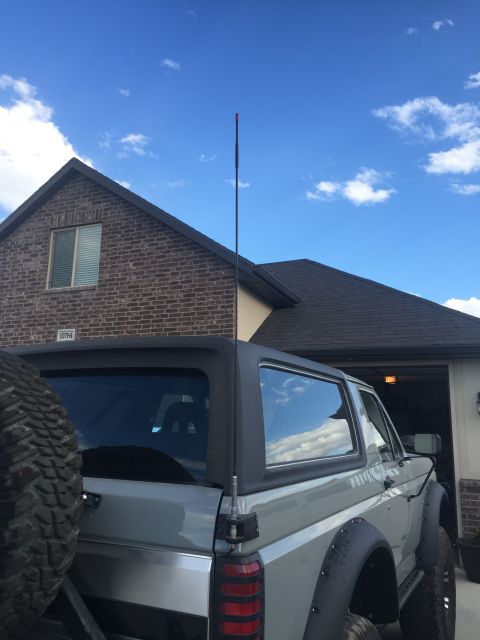 1988 Ford Bronco - The rear passenger side of a gray Ford Bronco is shown parked in front of a brick house with a dark roof. A tall antenna extends from the r…