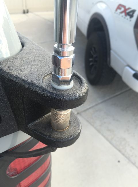 1988 Ford Bronco - A close-up shot shows a silver antenna mount attached to a textured black bracket on the rear of a vehicle. A white Ford F-150 FX4 is visib…