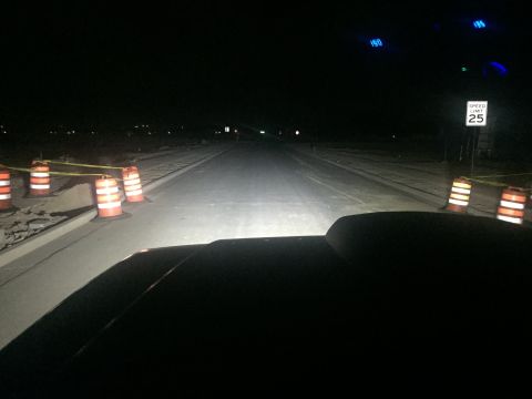 1988 Ford Bronco - View from inside a vehicle at night, looking down the road illuminated by headlights, with construction barrels visible.