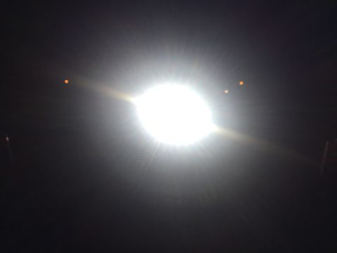 1988 Ford Bronco - A bright light dominates the frame, with two small orange lights in the distance.