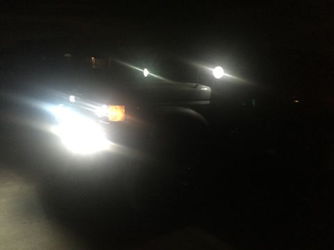 1988 Ford Bronco - Truck headlights illuminate the darkness, showing an amber turn signal on the front.