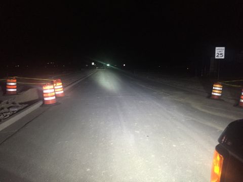 1988 Ford Bronco - The bright headlights of an unseen vehicle cut through the darkness on a road marked with traffic cones and a speed limit sign.