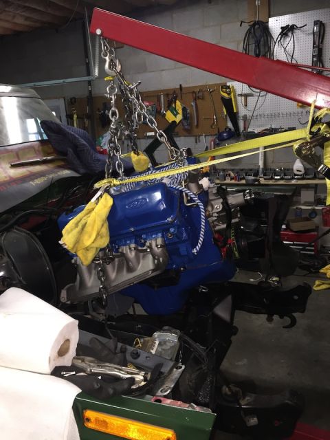 1978 Ford Bronco - Engine hoist lifting a blue Ford engine out of a vehicle in a garage.