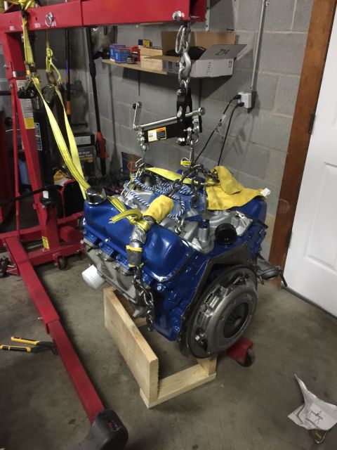 1978 Ford Bronco - Engine assembly is being lifted by a red engine hoist in a garage setting.