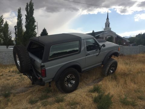 1988 Ford Bronco - Gray 1988 Ford Bronco with a soft top and spare tire mounted on the rear.