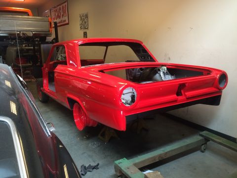 1964 Ford Fairlane - This red coupe is in a garage, missing doors and with an empty trunk, suggesting it's mid-restoration.