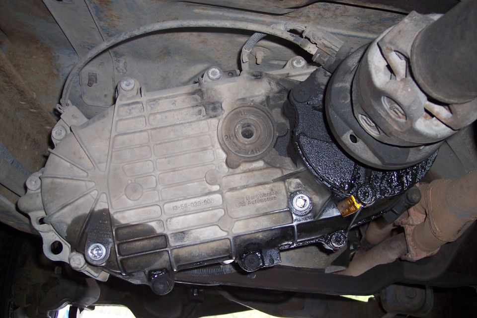 Transfer case with oil leaks and driveshaft connection. Part number visible