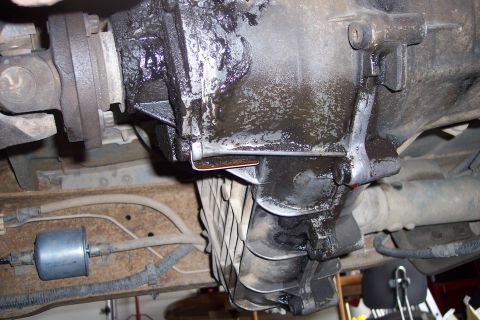 1990 Ford Bronco - Close-up of the vehicle's transmission and driveshaft, showing signs of wear and oil leakage.
