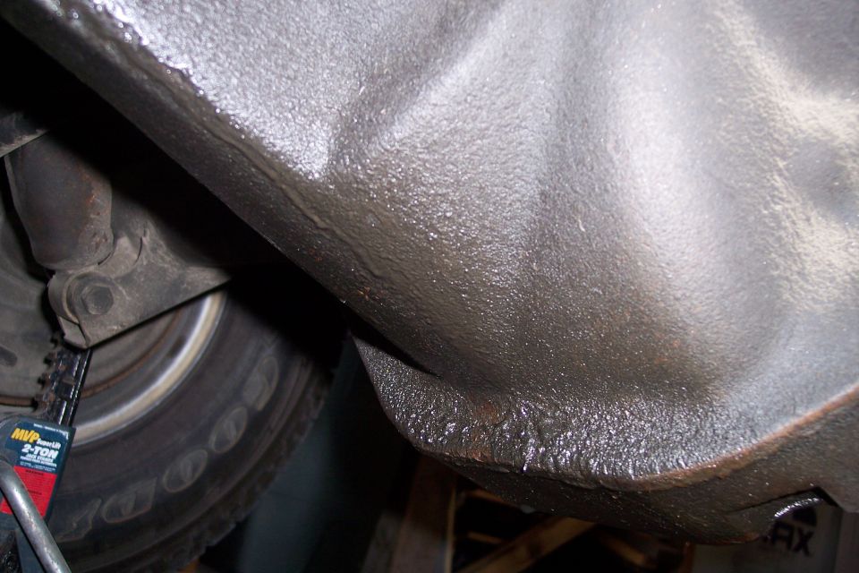 Underside of a vehicle, showing the frame and a tire on a jack
