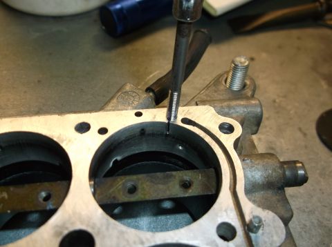 1979 Ford Ranchero - A tool is used to tap a hole in a metal carburetor part, likely for repair or modification.