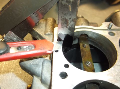 1979 Ford Ranchero - A mechanic uses tools to measure a gap on a carburetor part.