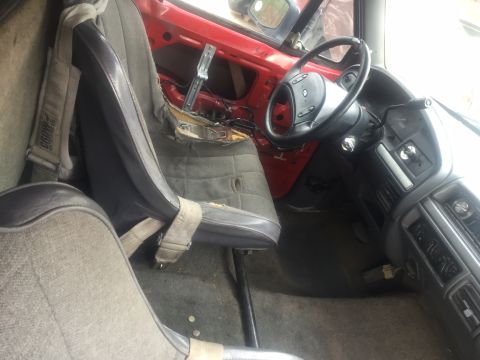 1986 Ford Bronco - The interior of a vehicle shows racing seats and exposed door mechanisms, with a Supermotors.net watermark.