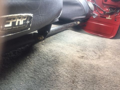 1986 Ford Bronco - Close-up of a racing seat interior, showing a PRP label and part of the vehicle's red door panel.