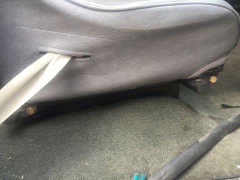 1986 Ford Bronco - Close-up view of a seatbelt and seat base inside a vehicle.