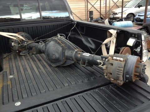 1995 Ford Bronco - A heavy-duty rear axle assembly is secured with straps in the cargo bed of a pickup truck.