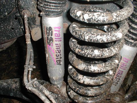 1995 Ford Bronco - Close-up view of a Trail Master SSV shock absorber and a dirty coil spring, likely from an off-road vehicle.