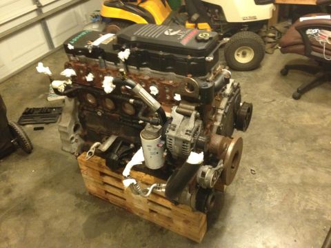 1995 Ford Bronco - A diesel engine sits on a pallet in a garage, with lawnmowers in the background.