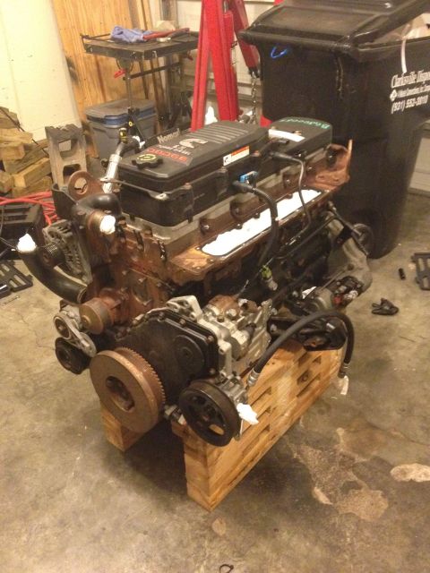 1995 Ford Bronco - A Cummins 5.9L diesel engine is shown resting on wooden blocks in a garage setting.