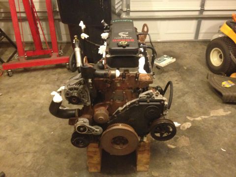 1995 Ford Bronco - A Cummins Dodge diesel engine is shown mounted on wooden blocks in a garage setting.