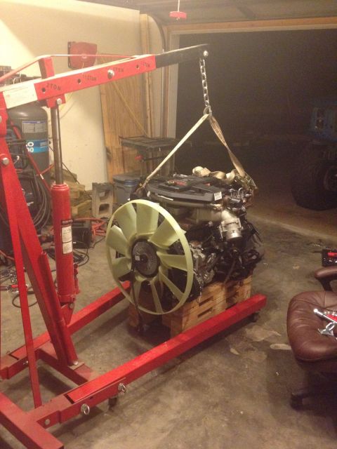 1995 Ford Bronco - An engine is suspended by a red engine hoist, ready for installation or removal.