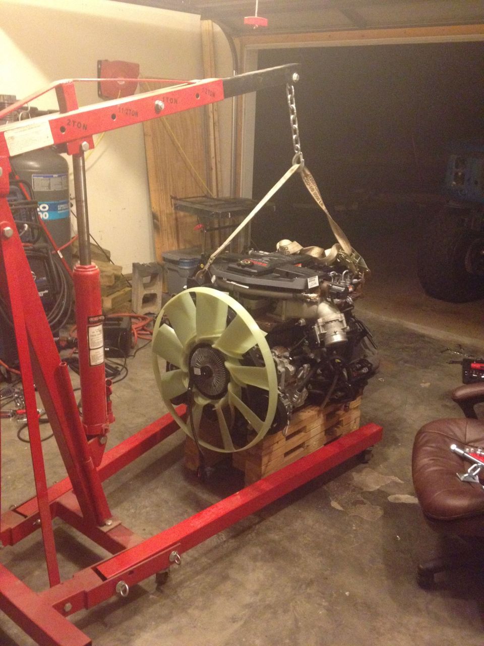 engine being lifted by a red engine hoist, sitting on wooden pallets