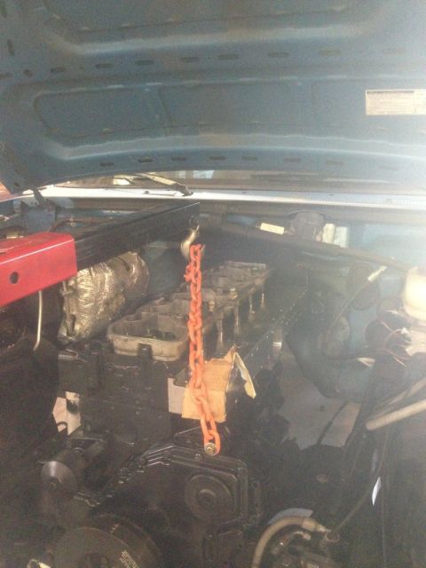 1995 Ford Bronco - Engine bay with an orange chain lifting engine parts, under a blue hood.