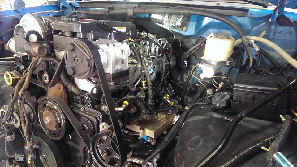 Engine bay with diesel engine components, including supercharger, belts, and hoses