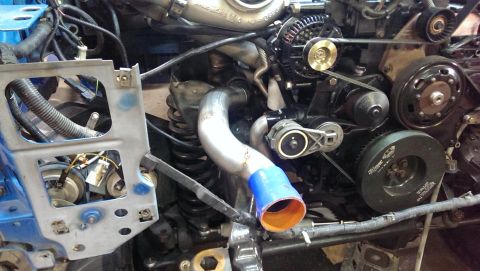1995 Ford Bronco - Close-up view of an engine bay, highlighting the turbocharger, alternator, and belt system. Features a blue and orange silicone coupler.