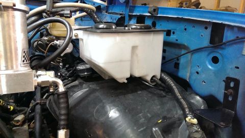1995 Ford Bronco - Close-up of a windshield washer fluid reservoir in an engine bay.