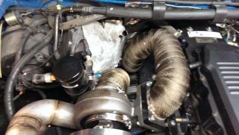 1995 Ford Bronco - Close-up view of a modified engine bay, highlighting a turbocharger and exhaust system with heat wrap.