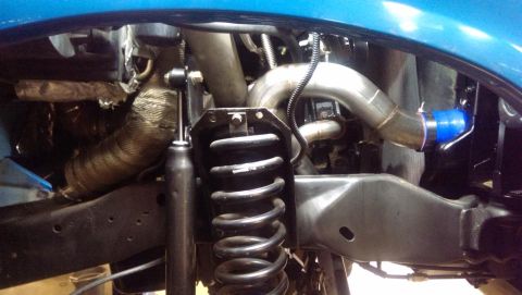 1995 Ford Bronco - Custom exhaust and turbo piping visible in a vehicle's engine bay, alongside suspension components.