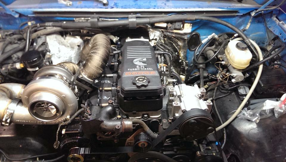Engine bay with a Cummins 6.7L turbo diesel engine, large turbocharger, and blue painted inner fenders