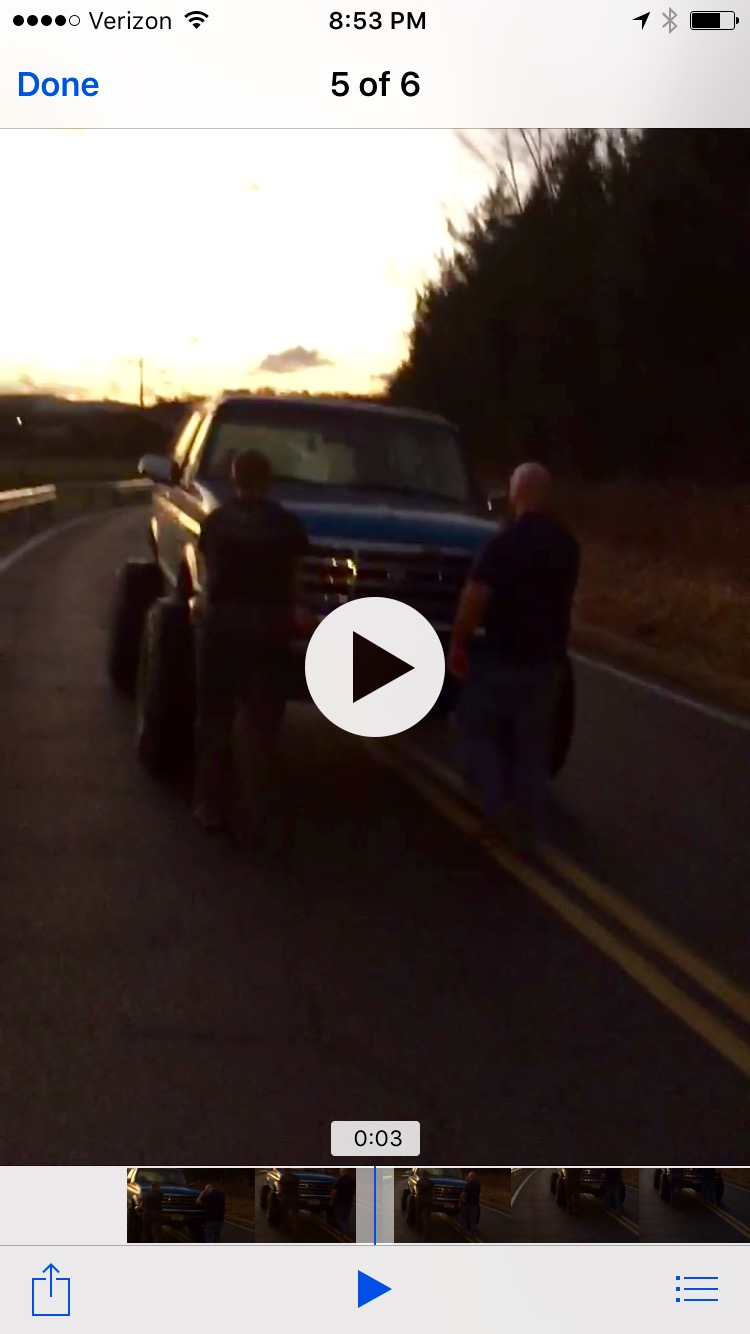 Blue pickup truck with large tires on a road at sunset