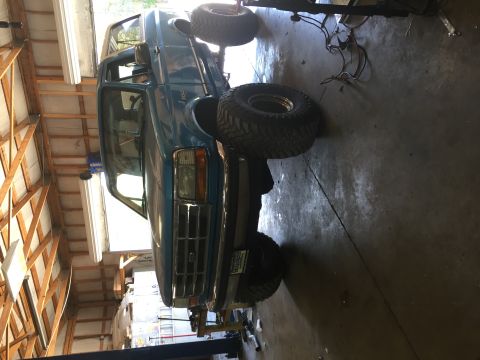 1995 Ford Bronco - A blue 1995 Ford Bronco is shown on a lift in a garage, with its front end prominently displayed.