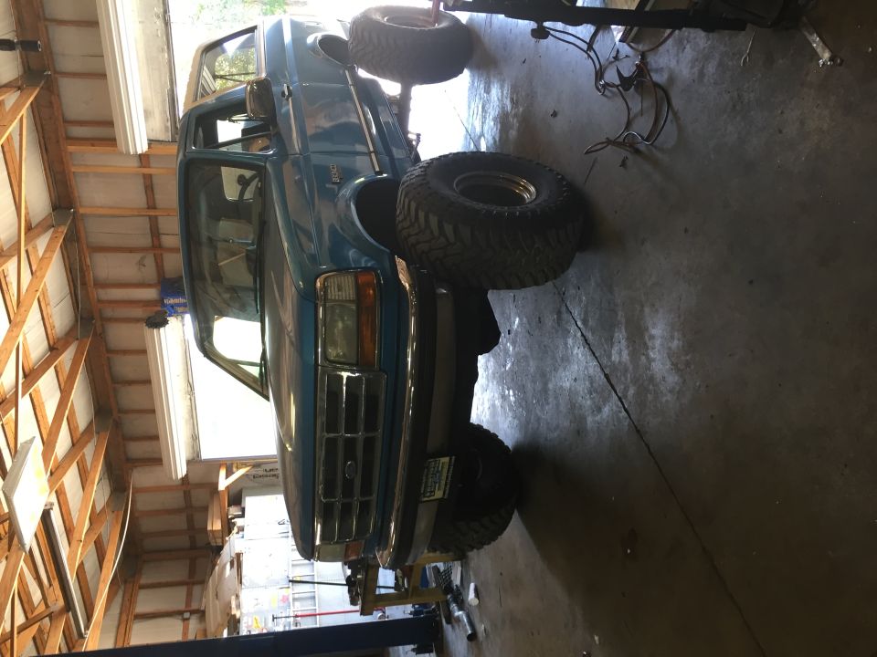 Blue 1995 Ford Bronco front grille and headlights on a lift