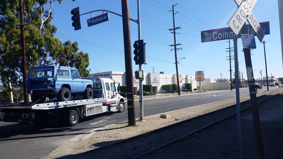 Light blue classic SUV on a flatbed tow truck, side view.