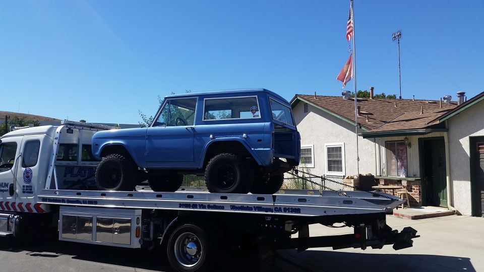 Blue Ford Bronco on a flatbed tow truck