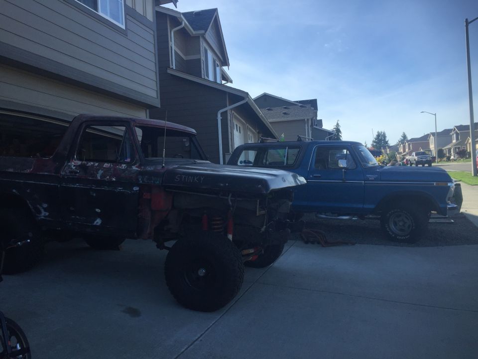 A dark red Ford Bronco project next to a blue Ford Bronco.