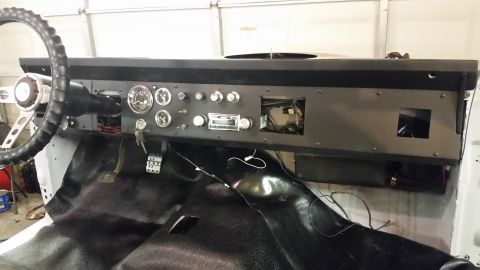1979 Ford Bronco - The interior of a vintage Ford Bronco shows a custom black dashboard with various gauges, a radio, and a steering wheel. The floor is cover…