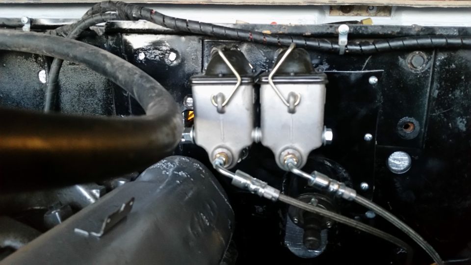 Dual brake master cylinder assembly on a black firewall.
